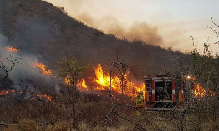Bomberos trabajan para sofocar el avance de las llamas por las sierras, entre Las Albahacas y Achiras